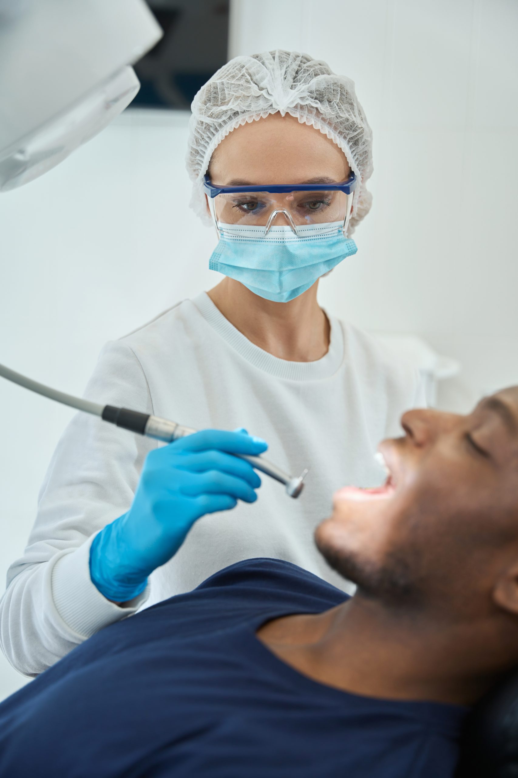 Woman dentist preparing to clean patient’s teeth